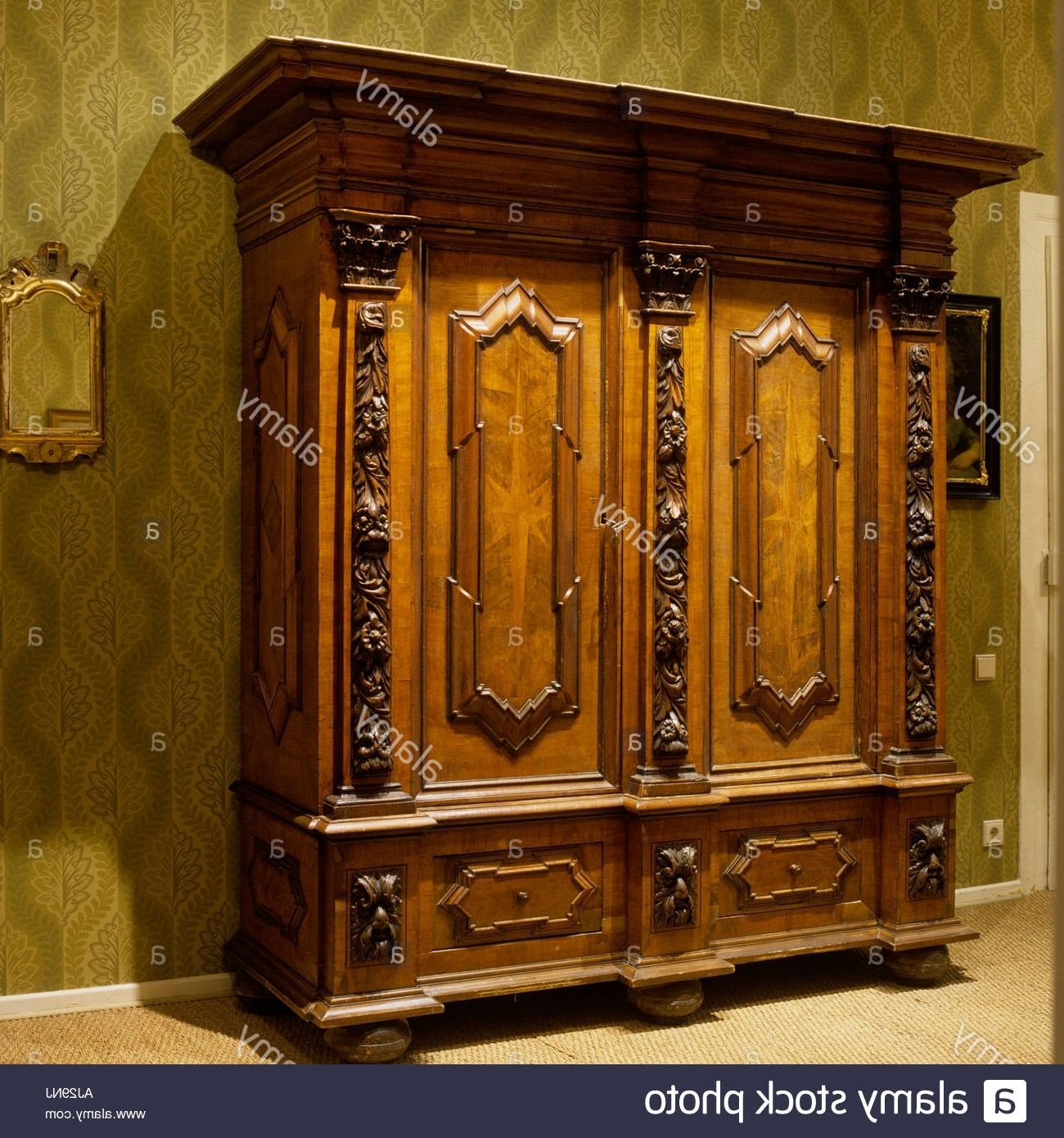 Ornate Wardrobes Throughout Well Known Ornate Antique Wooden Wardrobe With Green Patterned Wallpaper (Photo 1 of 15)