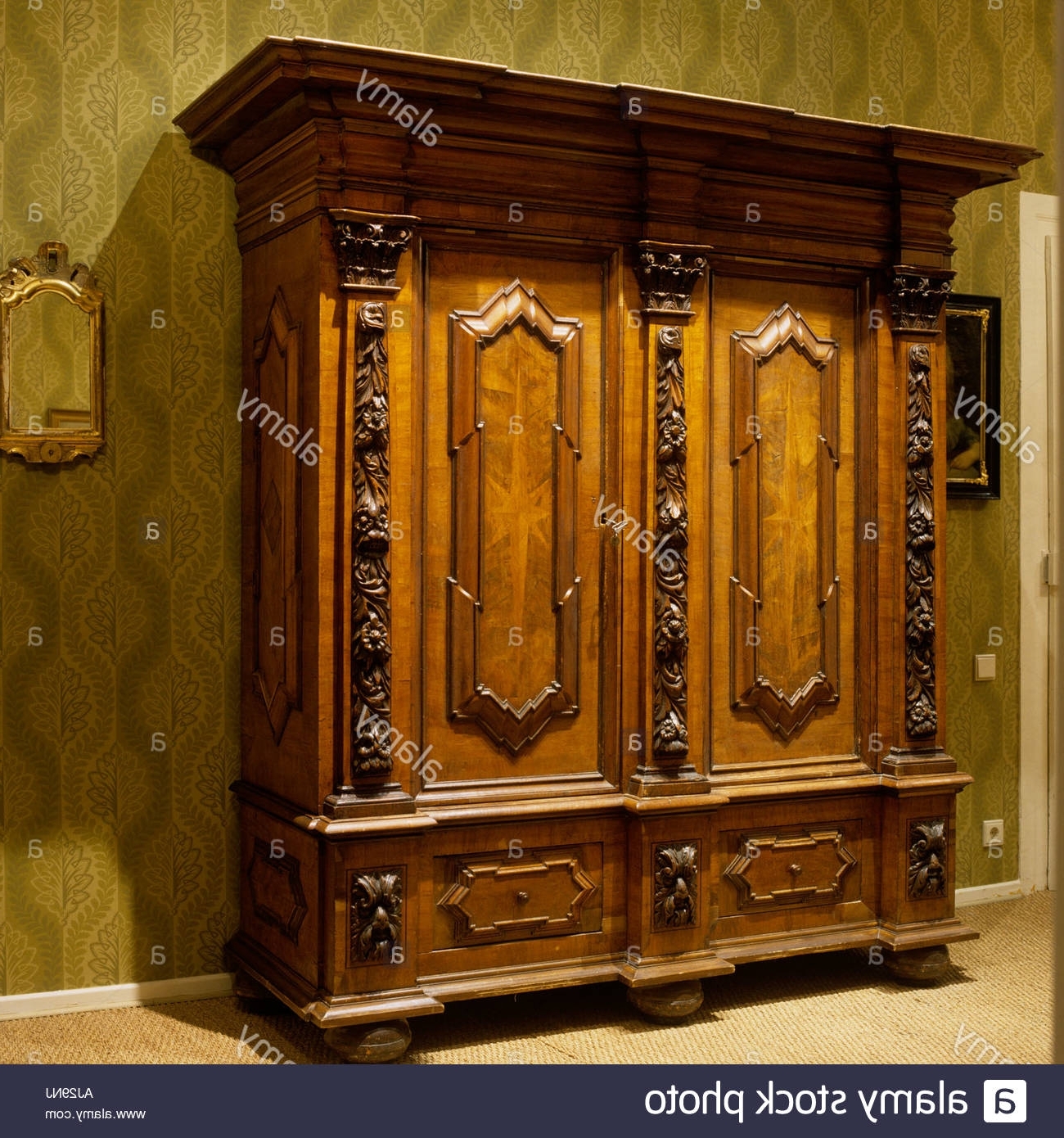 Ornate Wardrobes Throughout Well Known Ornate Antique Wooden Wardrobe With Green Patterned Wallpaper (Photo 1 of 15)